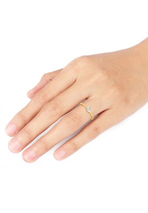 Guldring med perleindlæg og en diamant i midten med tre tænder, båret på en hånd med en naturlig hudtone.