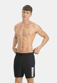 Bañador negro con cintura elástica, que presenta un destacado logo blanco de Puma en el lado izquierdo. Fabricado con un tejido suave y diseño de longitud hasta la rodilla.