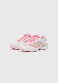 Lightweight athletic shoes feature a white synthetic upper with pink accents and mesh detailing, a cushioned sole, and three beige stripes.