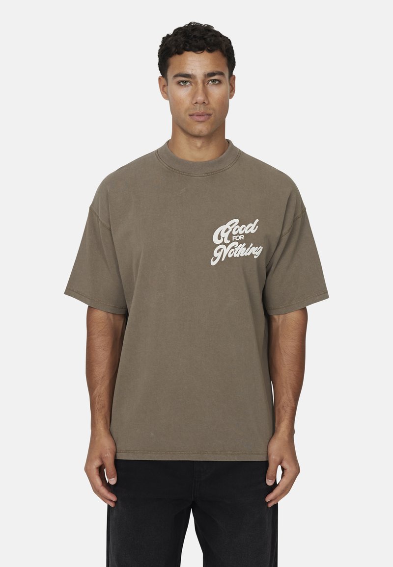Brązowy, oversize'owy t-shirt z bawełny, z krótkimi rękawami, z białym napisem "Good for Nothing" na lewej piersi. Minimalistyczny design.
