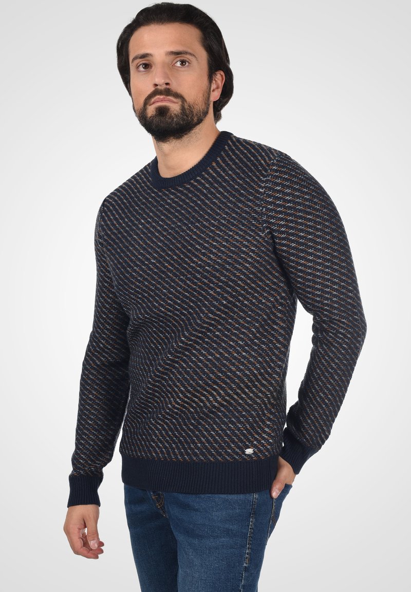Marineblaues Strickpullover mit diagonaler Musterung, gerippten Bündchen und Saum, mit dezenten orangefarbenen und beigen Akzenten. Klassisches Rundhals-Design.