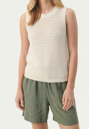 Crème gebreide mouwloze top met een gestructureerd patroon en geribbelde zoom, gecombineerd met losse olijfgroene linnen shorts.