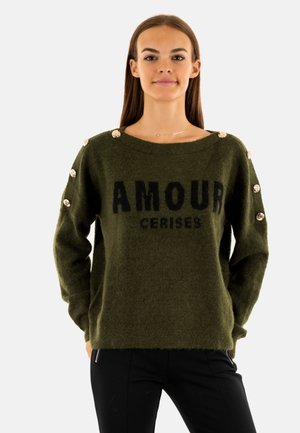 Maglione lavorato a maglia verde oliva con testo "AMOUR CERISES". Presenta grandi bottoni lungo le spalle e un collo ampio. Morbido al tatto, vestibilità comoda.