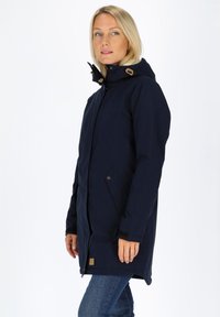 Granatowa wodoodporna kurtka z przymocowanym kapturem, bocznymi kieszeniami i brązowymi akcentami. Posiada zamek błyskawiczny z przodu i zapięcie na napy. Gładka faktura.