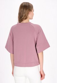 Top a maniche corte e collo rotondo in tessuto mauve tenue. Presenta maniche raglan, una vestibilità rilassata e una lunghezza corta. Finitura testurizzata.