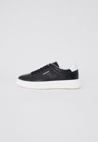 Fekete bőr sneaker fehér kiegészítőkkel, kerek orral, fűzős kialakítással és textúrált gumitalppal. Az oldalon logóval és perforált részletekkel rendelkezik.