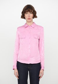 Pink snake-print shirt with a collared neckline, button front, and two chest pockets. Made from a shiny, smooth fabric; long sleeves.