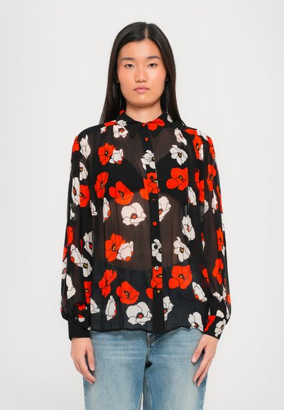 Blouse noire transparente avec un motif floral comportant des fleurs rouges, blanches et jaunes. Manches longues, col, fermeture à boutons sur le devant.