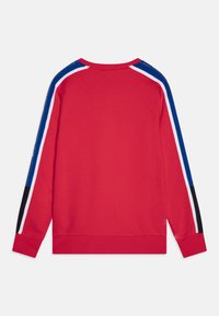 Sudadera roja con mangas largas, cuello redondo y acentos en bloques de color en azul, blanco y negro a lo largo de los hombros.