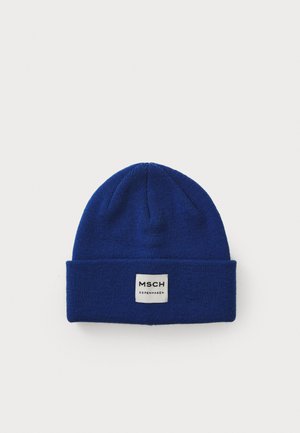 Blue knitted beanie with a folded cuff, featuring a white rectangular patch label with the text “MSCH COPENHAGEN.” Soft texture, solid color.