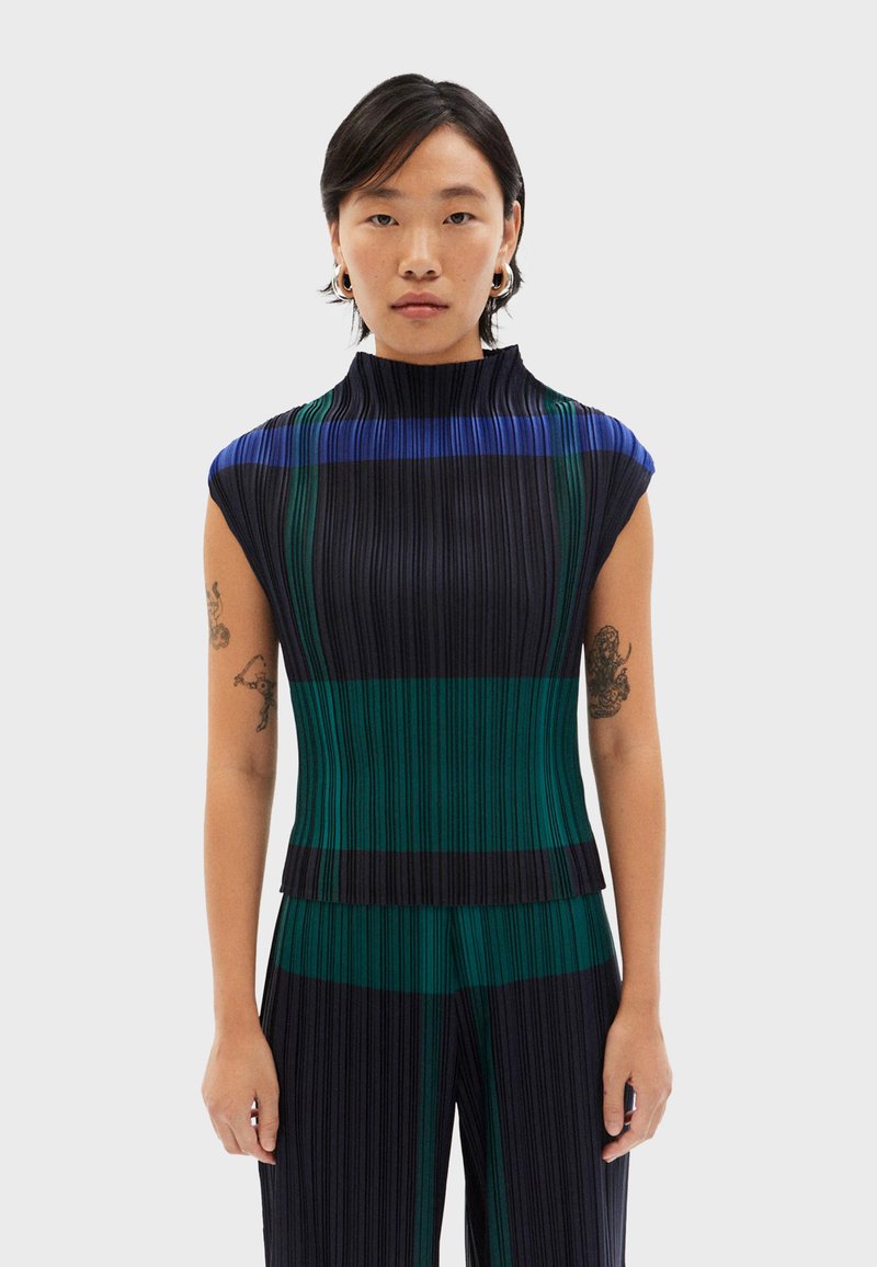 Top con pliegues y cuello alto; presenta rayas verticales en verde, azul y negro; la tela tiene un aspecto texturizado.