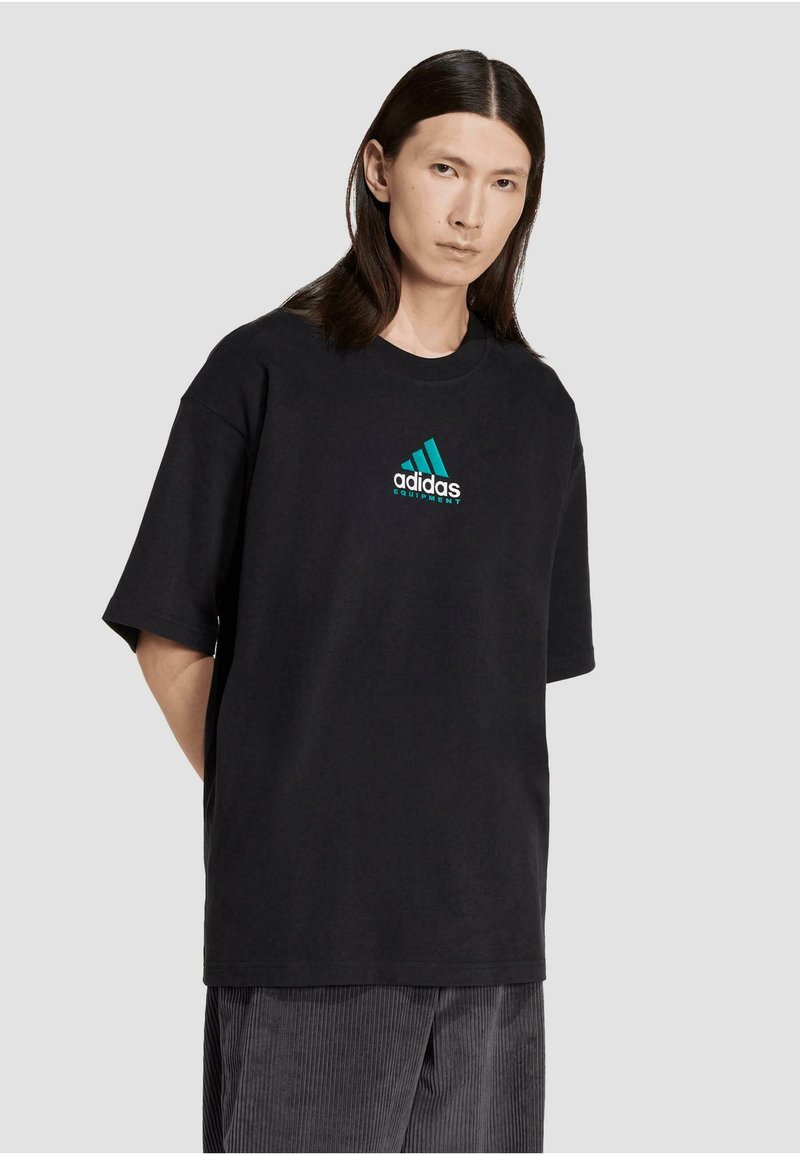 Sort bomulds T-shirt med rund halsudskæring, korte ærmer og et turkis Adidas-logo med tre striber på brystet.