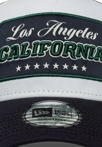 Μαύρο και άσπρο καπέλο με πράσινο κεντημένο κείμενο «Los Angeles CALIFORNIA» με αστέρια από κάτω. Ρυθμιζόμενο κούμπωμα με κουμπί στο πίσω μέρος.