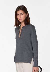 Grau langärmliger Pullover mit V-Ausschnitt und dekorativen Knöpfen. Er hat eine weiche Textur und seitliche Schlitze für eine bessere Bewegungsfreiheit.