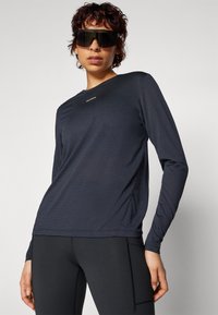 Langärmliges Sportoberteil in Marineblau, hergestellt aus leichtem Stretchmaterial. Verfügt über einen runden Halsausschnitt und minimalen Branding auf der Brust.