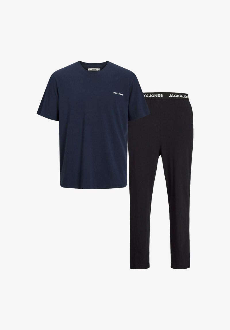Marineblauwe t-shirt met korte mouwen en een klein wit logo, gecombineerd met zwarte slim-fit broek met een witte merkband. Katoenen materiaal, zachte textuur.