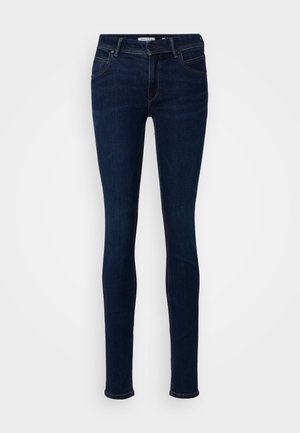 Schmale Jeans aus dunkelblauem Denim-Stoff. Verfügt über fünf Taschen, einen Knopfverschluss und dezente Nähte entlang der Säume.