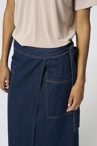Denim suknja u tamnoplavoj boji s dva prednja džepa, kontrastnim šavovima i vezanjem u struku. Glatka tekstura i A-linija.