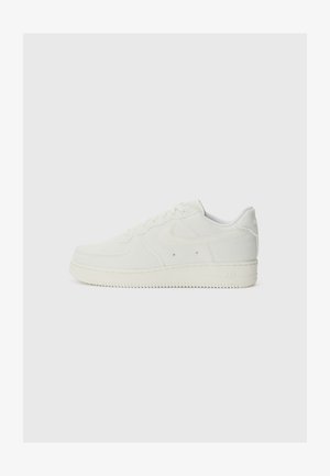 White Nike Air sneakers featuring a textured fabric upper, rounded toe, lace-up front, and embossed branding on the heel.