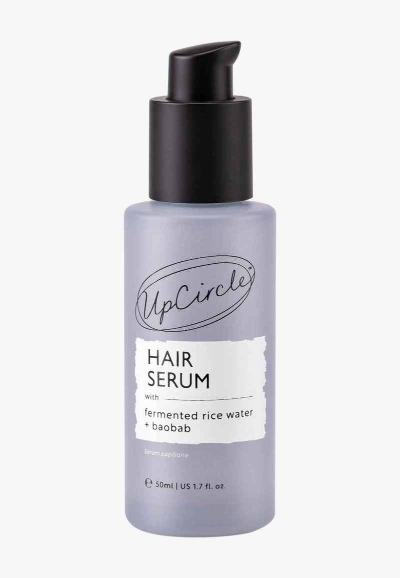 Lila frostad glasflaska med svart pump. Etiketten lyder "Hair Serum med fermenterat risvatten + baobab," 50 ml kapacitet.