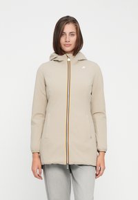 Lichtbeige jas met een capuchon, voorzien van een meerkleurige rits en elastische manchetten. Twee zijzakken en een klein logo op de borst.