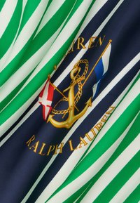 Πράσινο και λευκό ριγέ ύφασμα με ινδιγκό μπλε ρίγα που φέρει χρυσή άγκυρα και σημαίες, κείμενο «Ralph Lauren» σε χρυσή κεντητική.