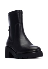 Stivale alla caviglia in pelle nera con una finitura liscia, suola platform spessa e punta rotonda. Presenta un sottile dettaglio cucito e accessori laterali.