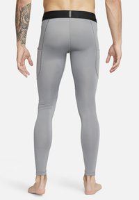 Lys grå treningsleggings med en jevn tekstur, med sort elastisk midjebånd og to sidelommer. Tett fit design.