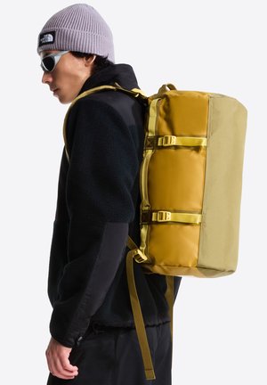Gele en olijfgroene rugzak met een rechthoekige vorm, gemaakt van duurzame materialen; voorzien van verstelbare banden en zijgespen.