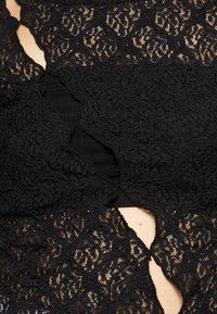 Black lace garment featuring intricate floral patterns, layered design, and a textured finish, with an underlying solid fabric section.