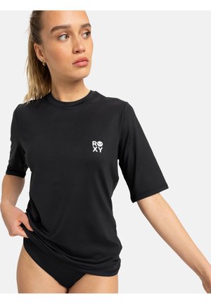 Black short-sleeve rash guard made of stretchy material, featuring a small white Roxy logo on the chest and ribbed accents at the hem.