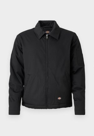 Black jacket with a zip front, pointed collar, side pockets, and a patch pocket on the left sleeve. Made of textured fabric, featuring a logo.