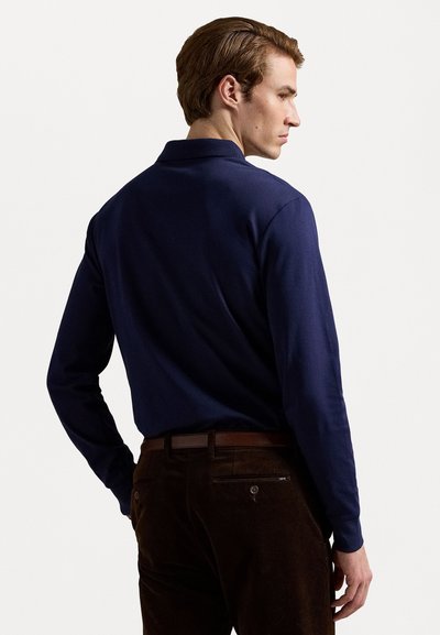 Long-sleeve navy polo shirt with a collar, paired with brown corduroy pants featuring back pockets and a belt.