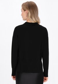 Schwarzer Pullover aus weichem Strickmaterial, mit lockerer Passform und geripptem Kragen. Zeigt ein einfaches, klassisches Design, das sich gut zum Layering eignet.