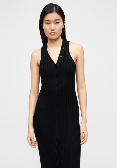 Vestido de malha preta canelada com decote em V profundo e design sem mangas, com botões frontais ao longo do comprimento. Textura suave com silhueta ajustada.