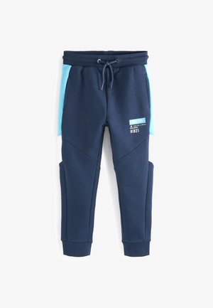 Marineblå joggingbukser med lyseblå og hvide sidelommer, elastisk talje med snøre og hvidt tryk på øverste venstre ben.