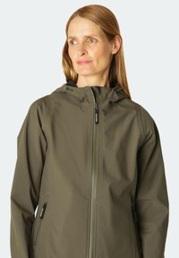 Veste imperméable vert olive avec capuche, fermeture éclair et deux poches latérales. Le matériau est lisse et léger avec une finition mate.