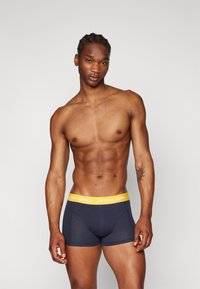 Navyblauwe boxershorts met een gele elastische tailleband voorzien van het "JACK & JONES" logo, gemaakt van een zachte, rekbare stof.