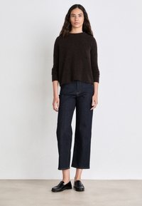 Brown, knit, long-sleeve top paired with high-waisted, dark blue, wide-leg jeans and black loafers. Simple, clean design, no patterns.