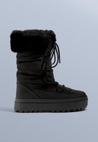 Schwarze isolierte Winterstiefel mit einem Kunstpelzkragen, gepolstertem Design und strukturierter Gummisohle. Mit Schnürung vorne und Logo-Detail.