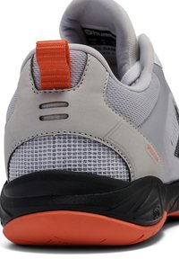Grijze sportschoen met meshpanelen, oranje accenten en een zwarte zool. Voorzien van een trekband aan de hak en een gestructureerd oppervlak.