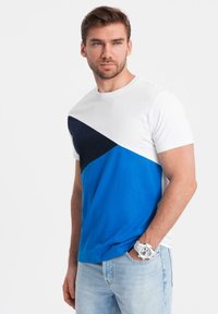 Tričko s krátkým rukávem s geometrickým designem v bílé, námořnické a modré barvě. Vyrobeno z měkké bavlny, s kulatým výstřihem.