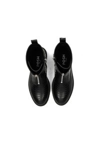 Botines negros con una superficie texturada y cremalleras a los lados, exhibidos sobre un fondo blanco. El logo de la marca es visible en el interior.