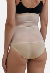 Reggiseno beige modellante con tessuto liscio e elasticizzato, design a vita media e bordo scalloppato. Spalline nere regolabili sul retro.
