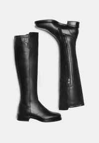 Bottes noires en cuir montantes avec un bout carré, texture lisse, fermeture éclair sur le côté et un petit talon carré. Elles présentent des détails de piquage sur la tige.