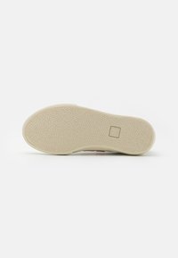 Kengän pohja, jossa on teksturoitu vaaleanbeige kumipinta, jossa on logo-työntö ja lievästi kaareva muoto ergonomista tukea varten.