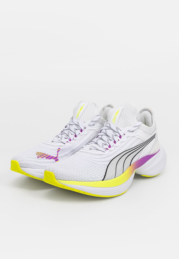 Chaussures de course avec un dessus texturé blanc, des rayures noires et une semelle jaune ; elles présentent des accents violets et des lacets à motifs.