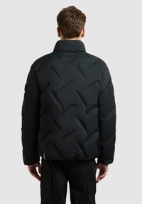 Zwarte gewatteerde jack met hoge kraag, voorzien van een chevron-stikpatroon en een gladde textuur. Inclusief een logo-detail aan de achterkant.