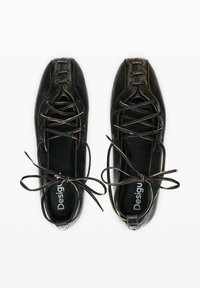 Black leather shoes with a rounded shape, featuring lace-up design, contrasting stitching, and a smooth texture. Logo visible inside.