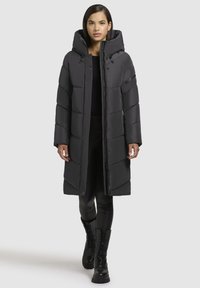 Must must coat kõrge kraega ja kapuutsiga. Omab vertikaalset tikandit, esimest tõmblukk ja küljetaskuid.